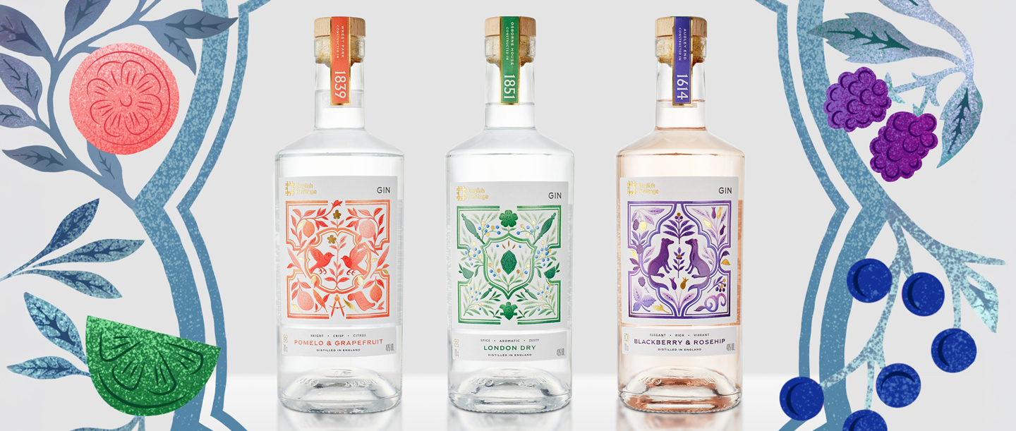 Three bottles of gin with colourful packaging from the Wiltshire Distilling Company created in partnership with English Heritage. They stand in front of a patterned background.