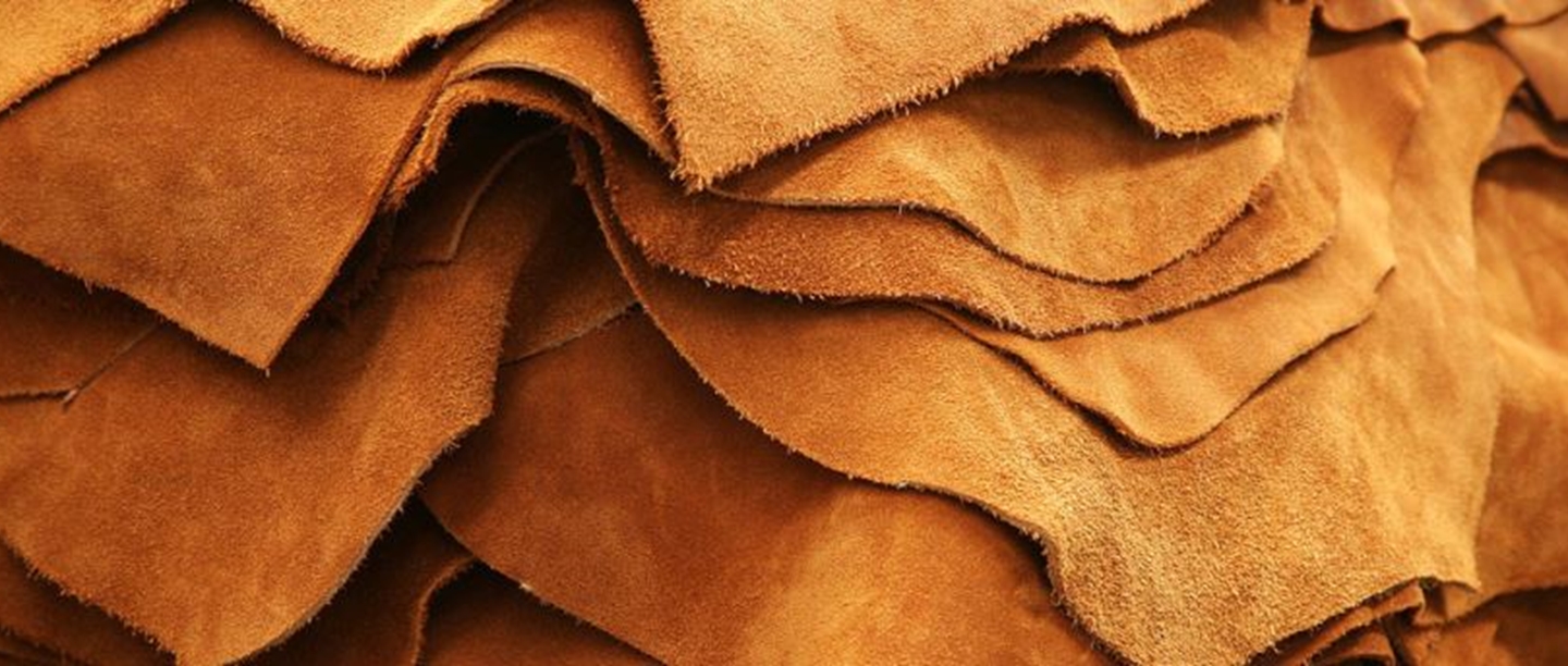 A pile of large sheets  of light brown leather.