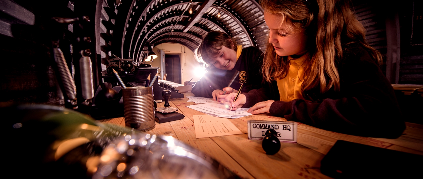 Two girls sit at a typewriter inside the Secret Wartime Tunnels at Dover Castle