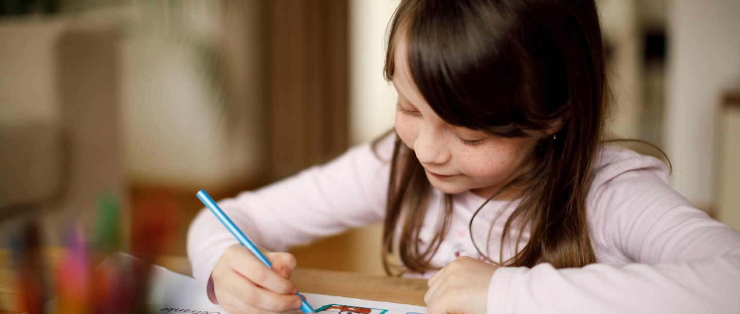 A young girl smiling and drawing a picture