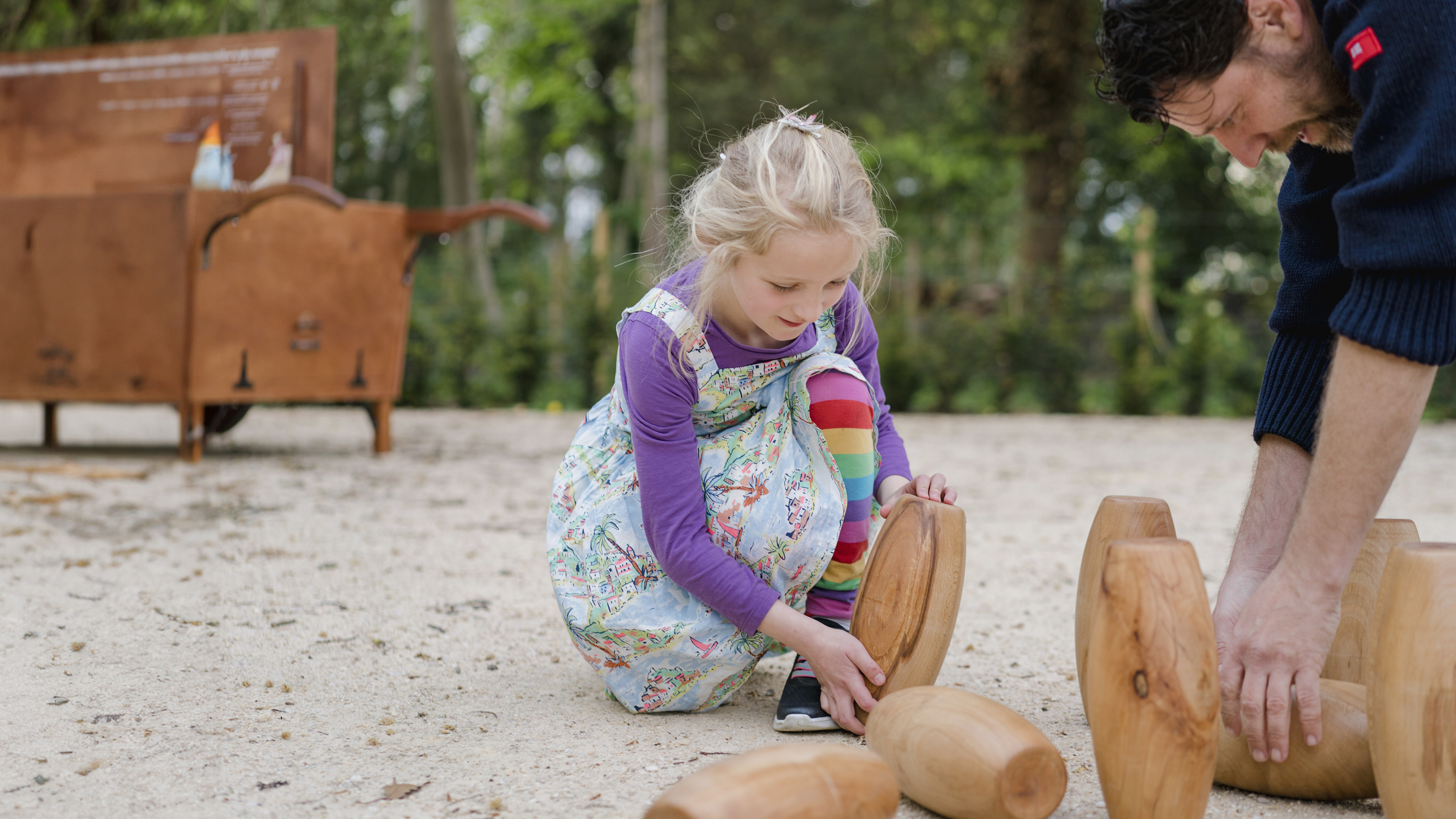 A young girl and her father place skittles on the ground