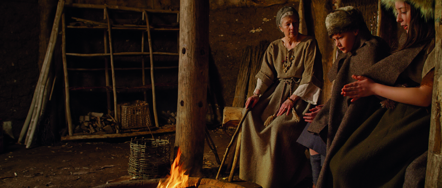 A re-enactor and two children dressed as Bronze Age settlers
