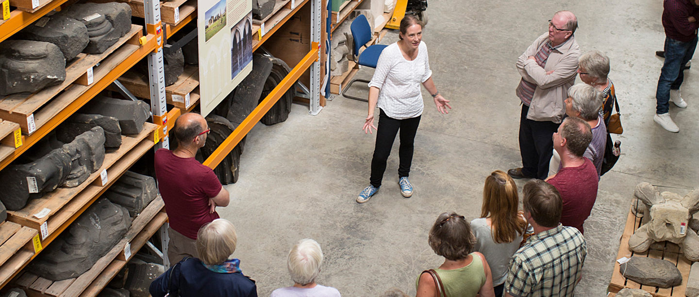 A tour guide talks to a group of people in Helmsley Archaeology Store.