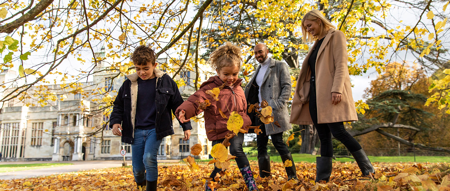 Two adults and two children walk through the gardens at Audley End in the autumn.