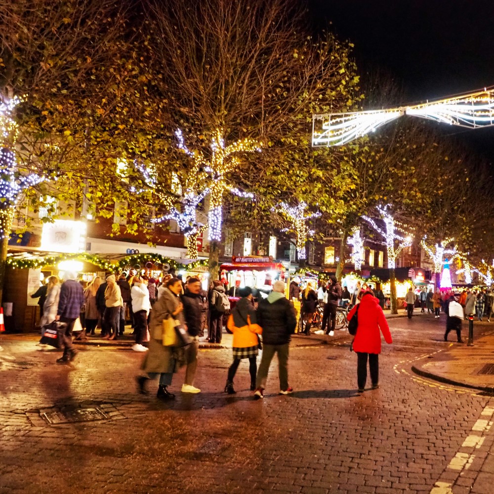 Photo of a busy street in York lit up with Christmas lights in the evening