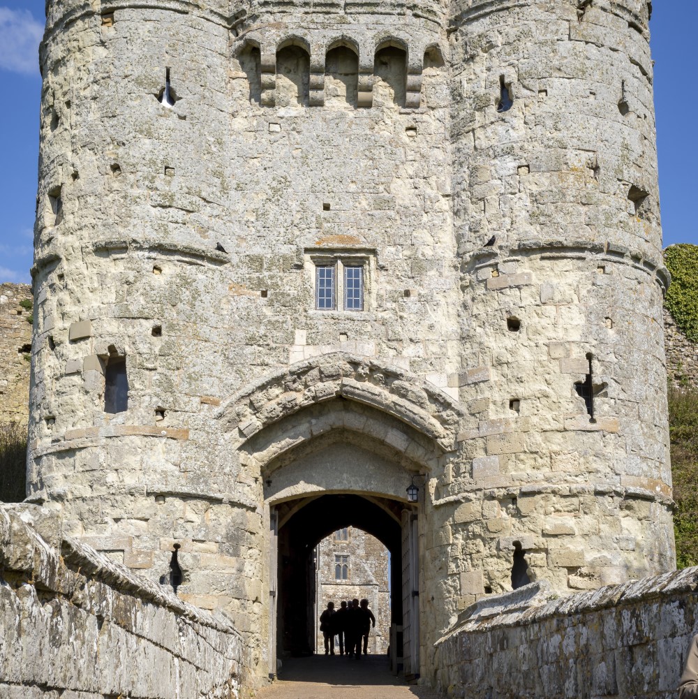 Photo of a group of people walking through the stone gatehouse at Carisbrooke Castle on a sunny day