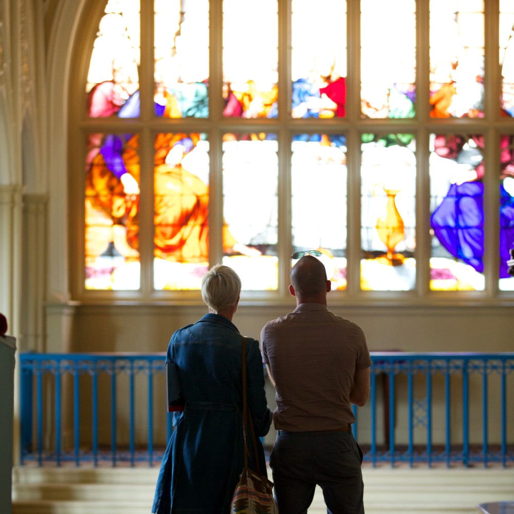 Photo of two people looking at a large stained-glass window at Audley End House in Essex