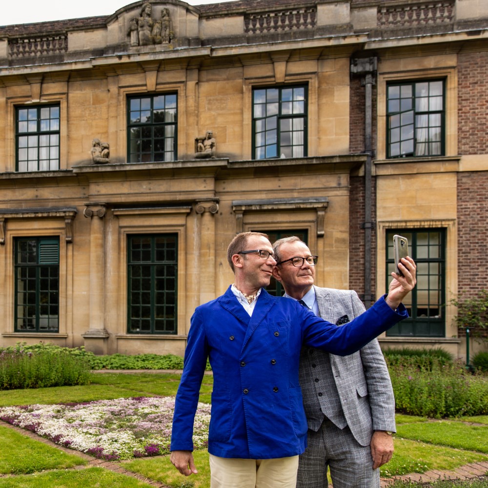 Photo of two people taking a selfie in front of Eltham Palace on a cloudy day