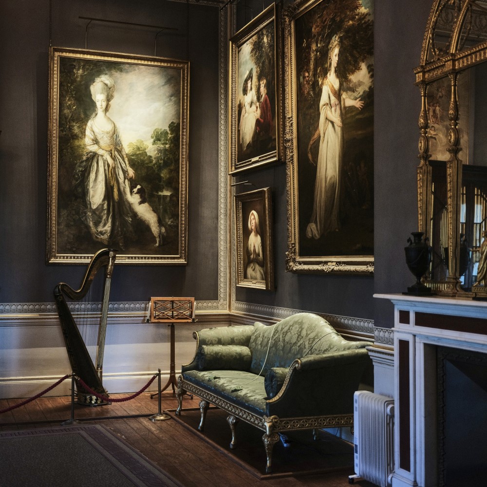 Photo of a harp, a sofa, and paintings in the music room at Kenwood House