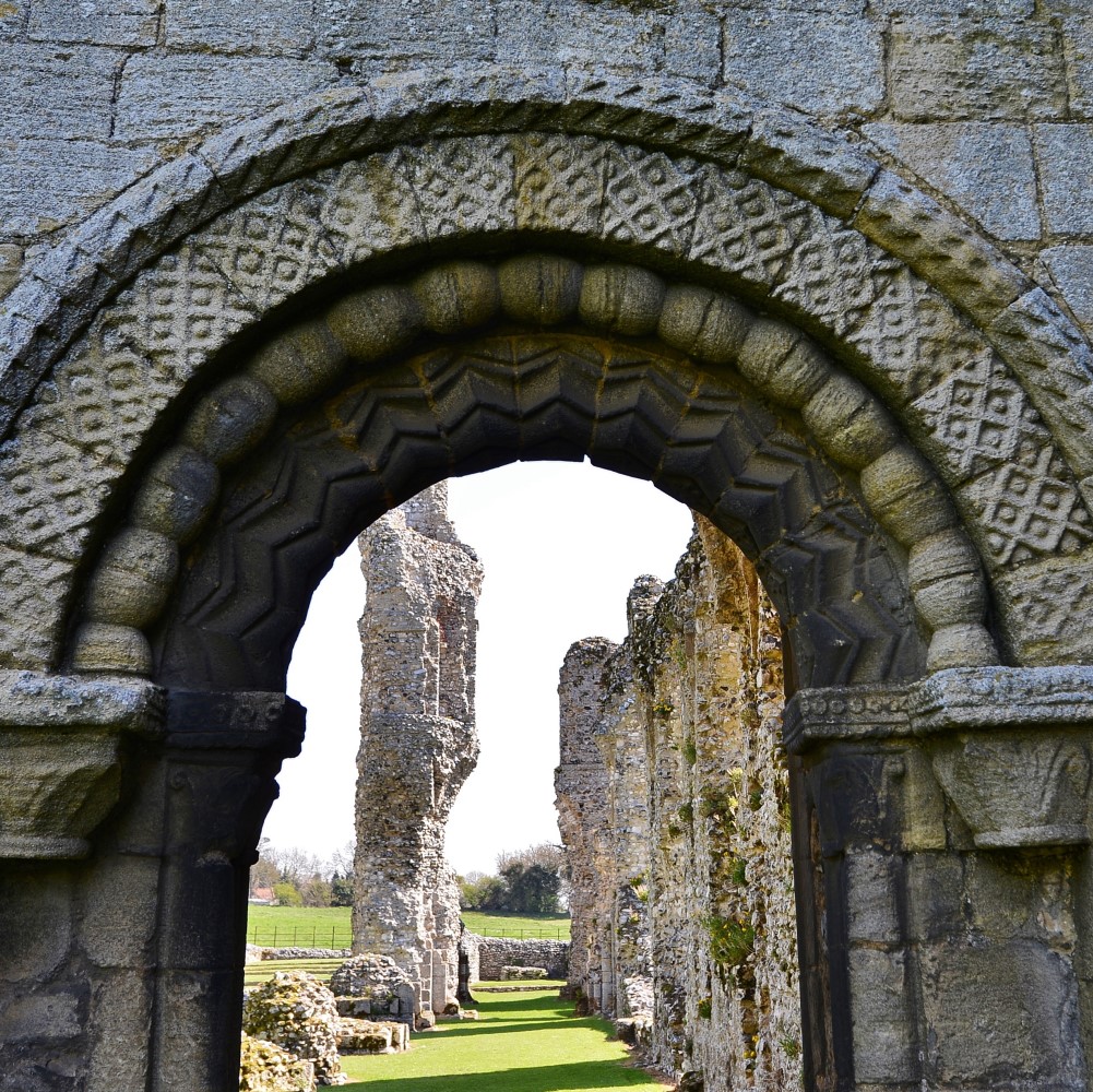 Photo of the remains of Castle Acre Priory seen through a stone archway