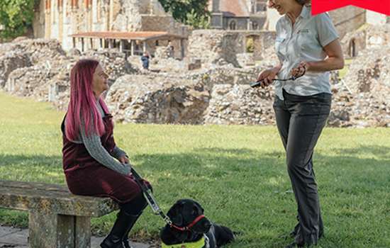 Image: partially sighted visitor with assistance dog talks to staff member at St Augustine's Abbey