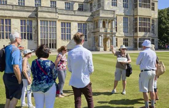 Photo of an English Heritage tour guide speaking to a group of visitors outside Audley End House in Essex