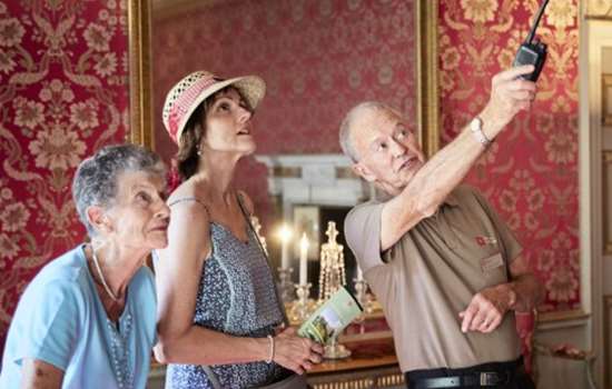 Photo of an English Heritage tour guide pointing out something to two visitors at Audley End House and Gardens in Essex