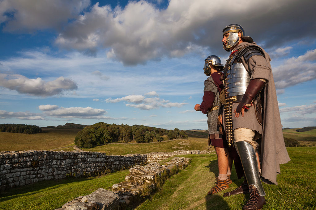 Image: A Roman re-enactor standing at Hadrian's Wall