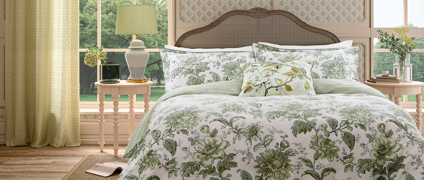 A view of a bed featuring green and white floral bedding from the English Heritage collection with Bedeck.