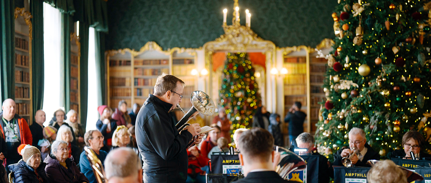 A brass band playing in one of the rooms at Wrest Park with Christmas trees in for a seated audience.