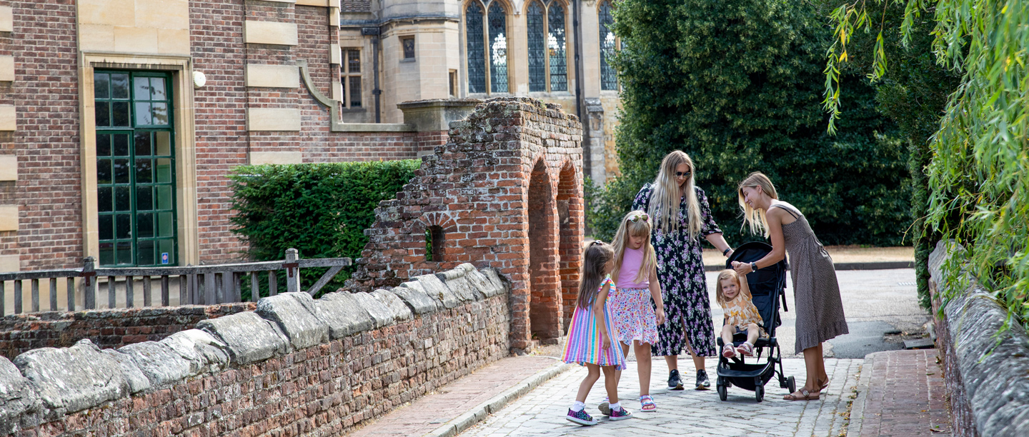 Two women with a pushchair and three children stand on the bridge at Eltham Palace. 