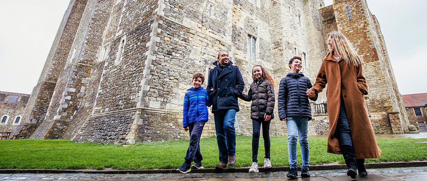 A family walking hand-in-hand outside Dover Castle