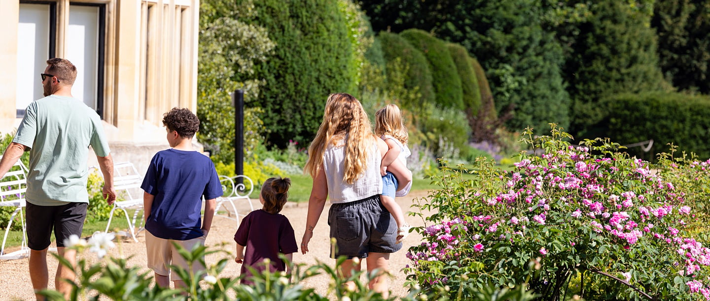 A man and a woman walk with two young children in the gardens at Audley End.