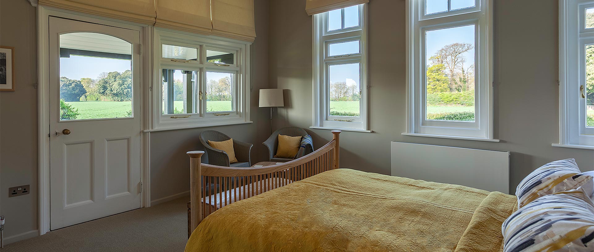 A light and airy bedroom with windows looking out across lush countryside