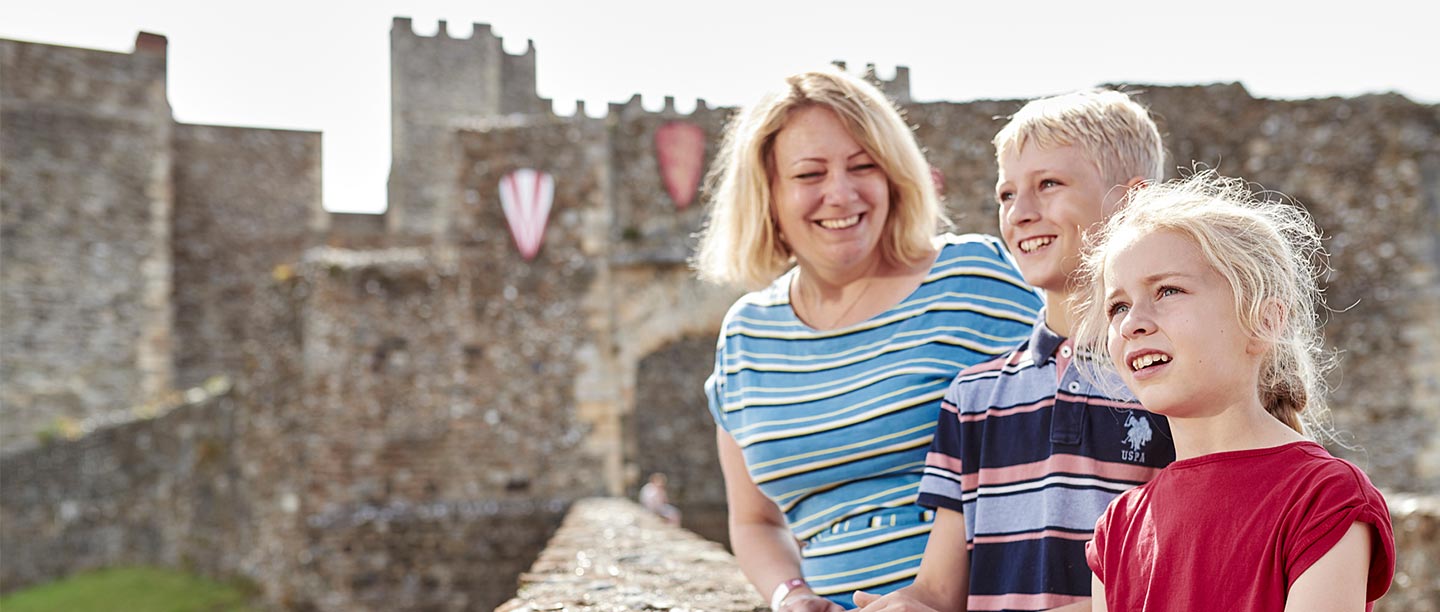 A woman and two children smile outside a castle