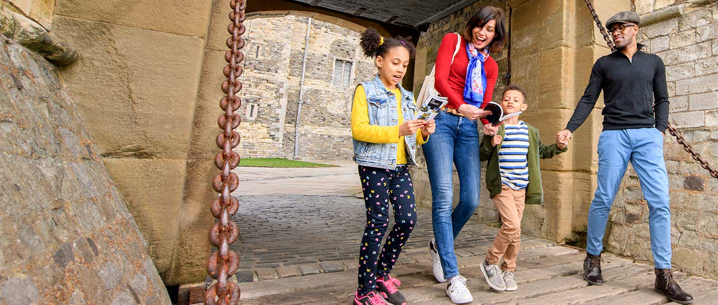A woman, man and two children walk through an old castle gateway