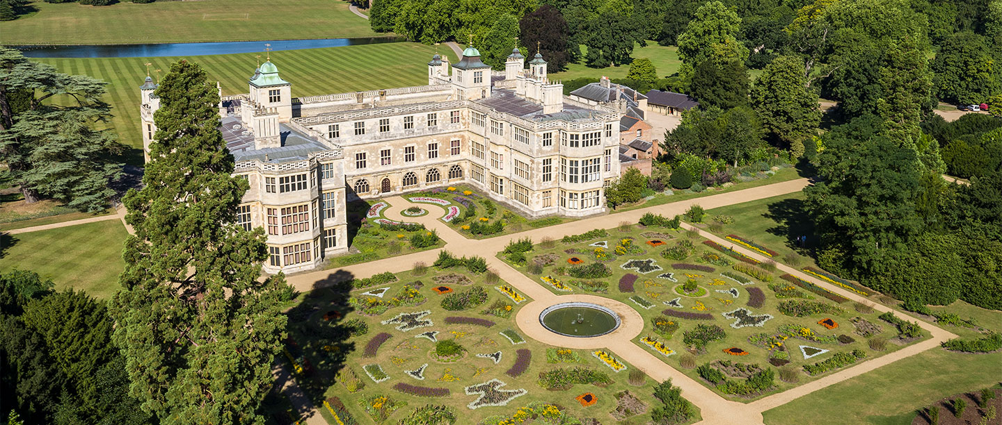 A grand mansion surrounded by beautiful gardens seen from above