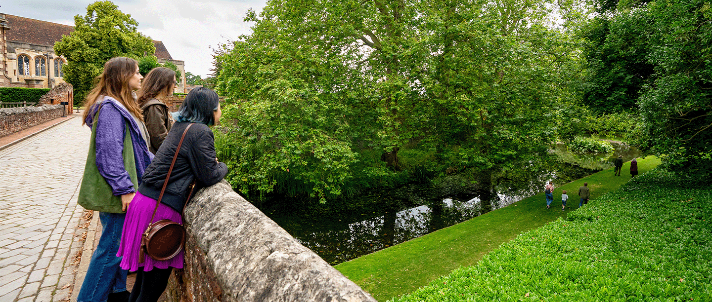 Photo of three young people looking out over the bridge at Eltham Palace and Gardens