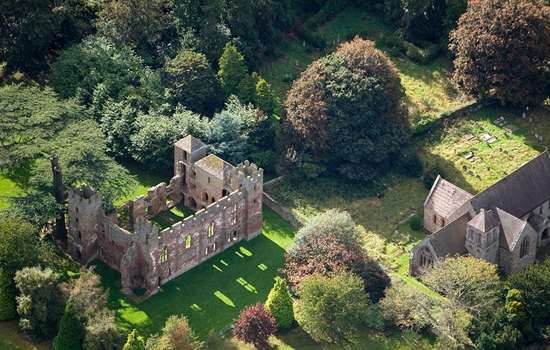 Aerial view of Acton Burnell Castle ruins alongside 13th century medieval St Mary's Church set amongst a rich planting of trees Aerial view of Acton Burnell Castle ruins alongside 13th century medieval St Mary's Church set amongst a rich planting of trees