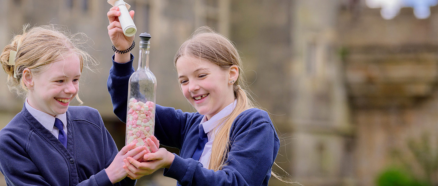 Two girls conduct an experiment with some marshmallows in a jar