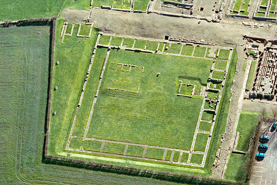 The courtyard building, known as Site XI, Corbridge Roman Town, its clear stone wall footings offset by verdant green lawn
