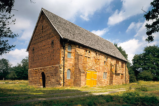 The north barn of Halesowen Abbey, incorporating medieval masonry and timbers, its yellow stone glowing in the warm sunshine