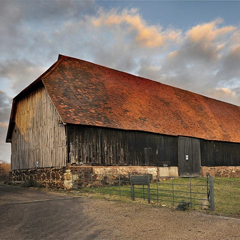 An old wooden barn with a rustic red roof