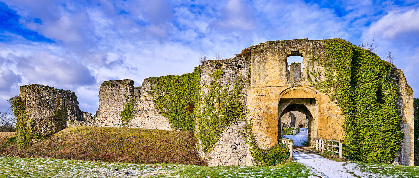 Helmsley Castle with frost on the grass underneath a blue sky.