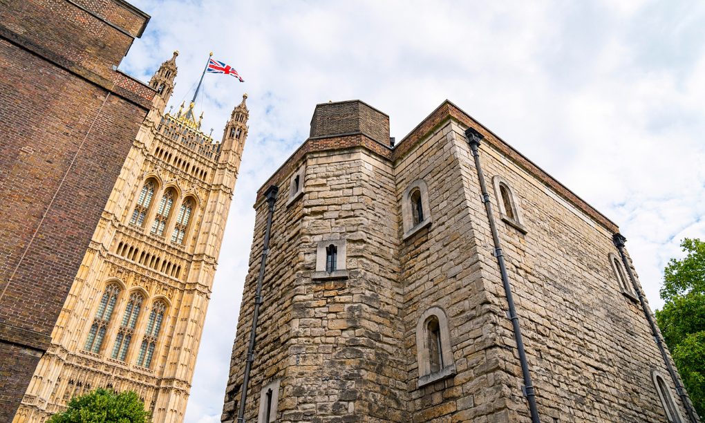 A low angle view of the stone Jewel Tower next to Westminster Abbey with a Union Jack flag.