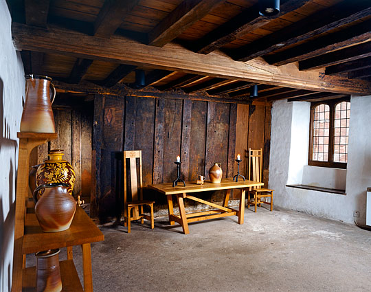 The parlour with low, heavy beamed ceiling and fine modern wooden furniture and pottery in traditional style
