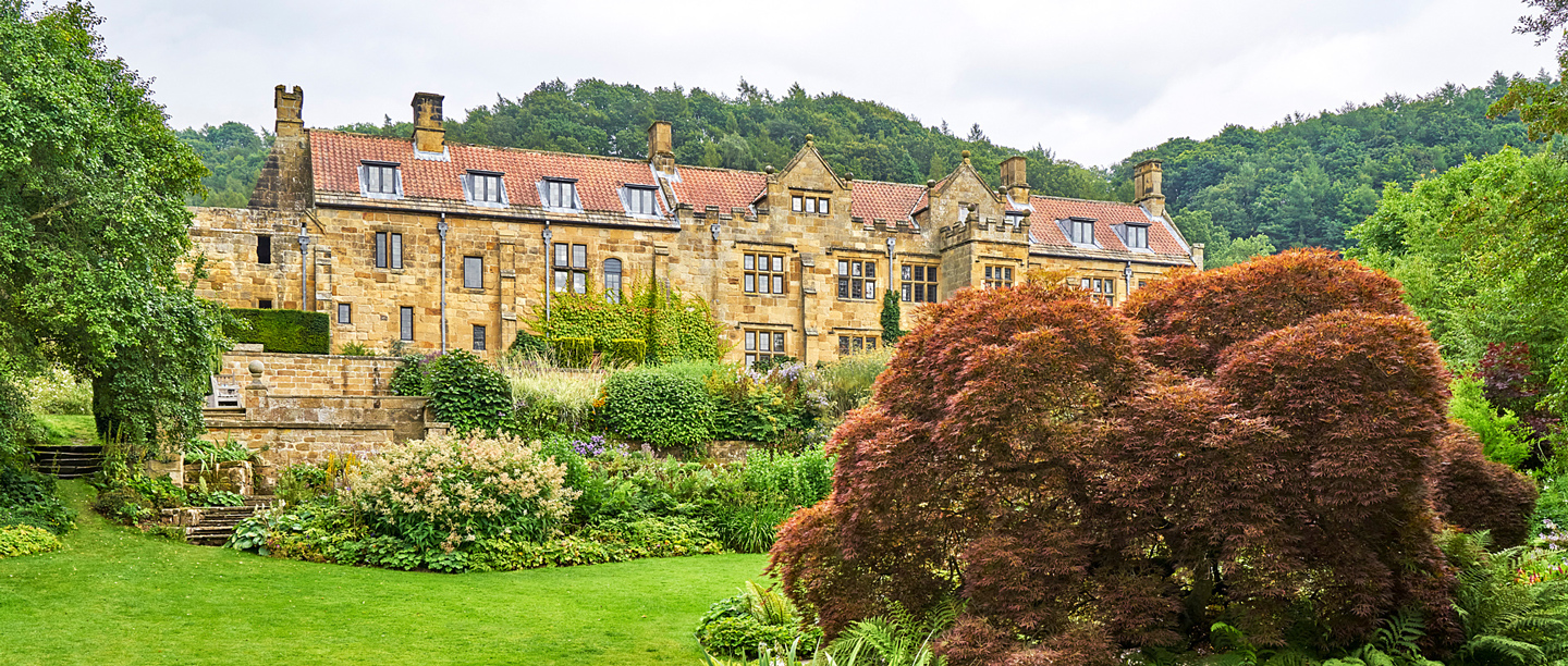 A view of the 17th century building in the grounds at Mount Grace Priory with the gardens in the foreground.