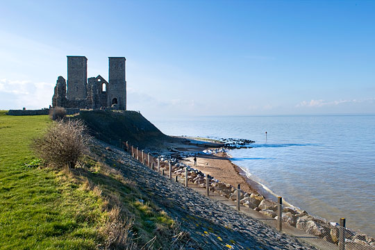 A view of the imposing towers of the medieval church at Reculver, standing on the edge of a low cliff above the rocky shore