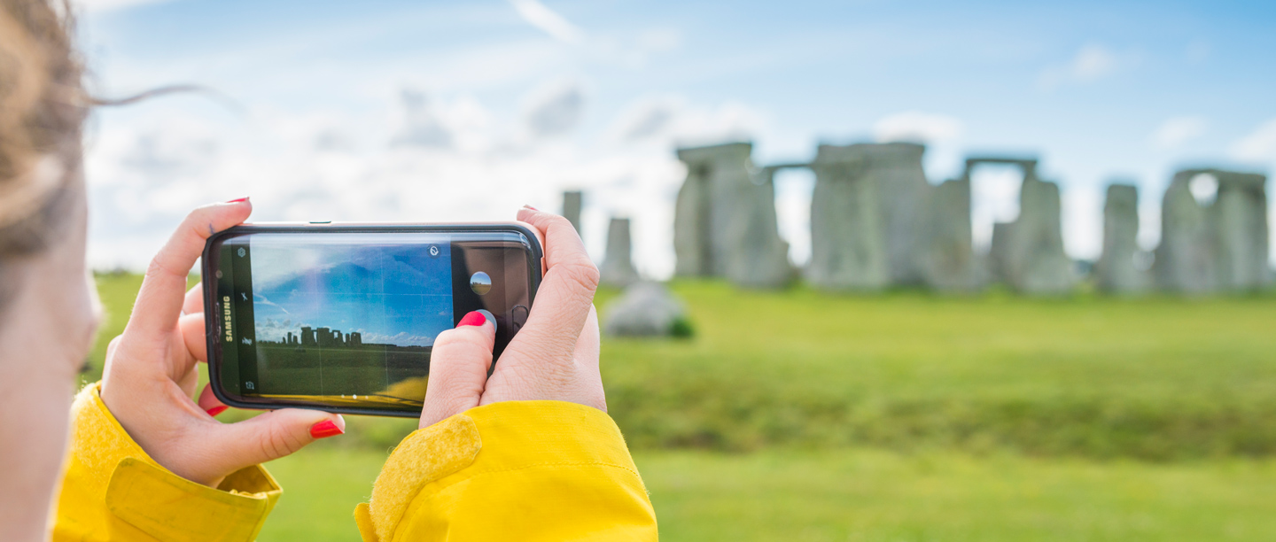 Someone takes a landscape photo on a mobile phone of Stonehenge.