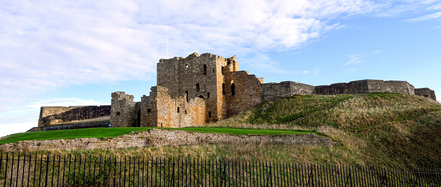 A low angle view of Tynemouth Priory on top of a hill.