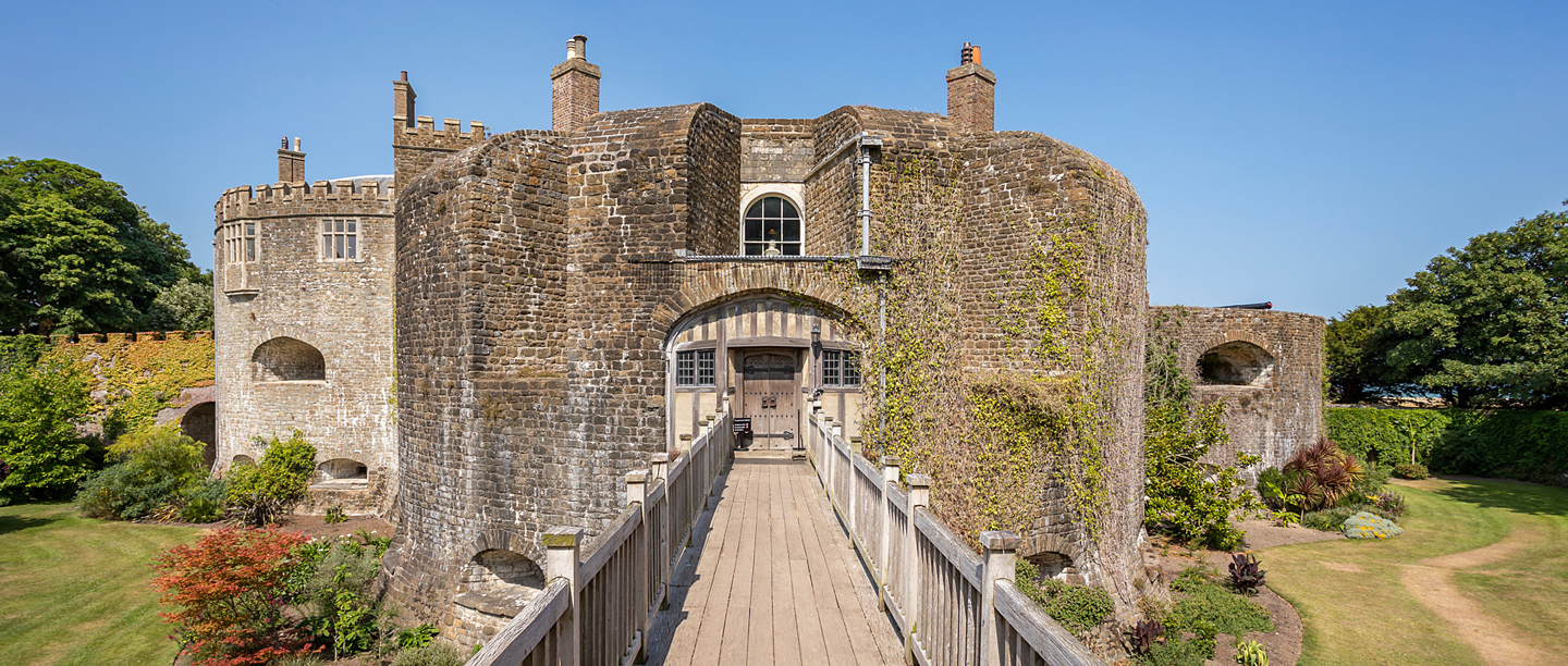 The entrance to Walmer Castle with view of a wooden bridge leading to the stone circular castle building.