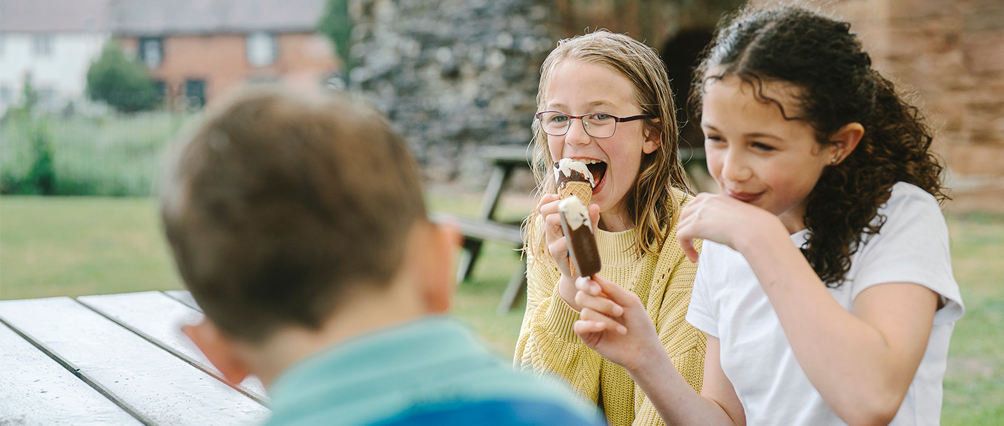 Two girls laugh while eating ice creams