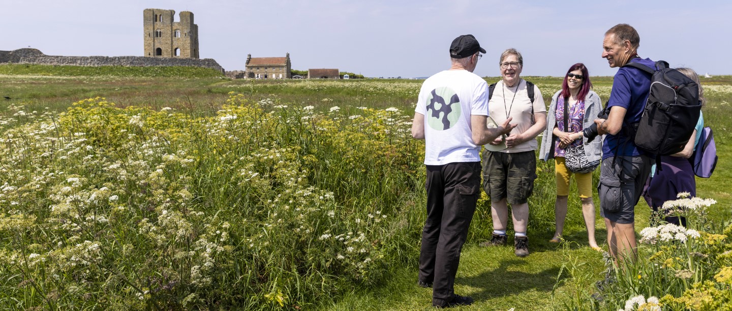 Photo of a group of people standing talking in a meadow at Scarborough Castle