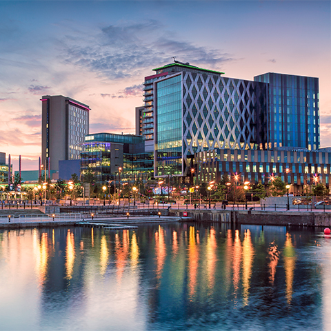 Large modern buildings viewed across water at sunset