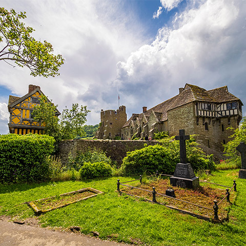 Looking across a churchyard to Stokesay Castle with its bright yellow gatehouse