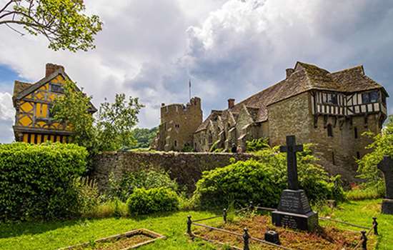 Looking across a churchyard to Stokesay Castle with its bright yellow gatehouse Looking across a churchyard to Stokesay Castle with its bright yellow gatehouse