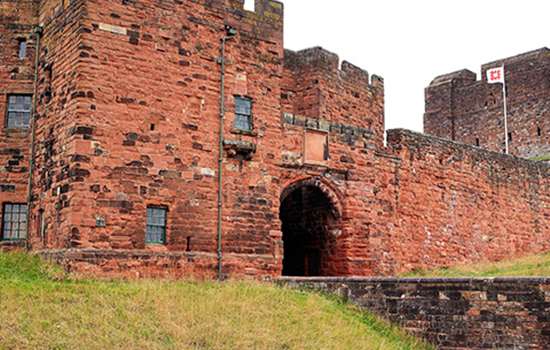 A large, red castle with a bridge leading to the front gate (Carlisle Castle) A large, red castle with a bridge leading to the front gate (Carlisle Castle)