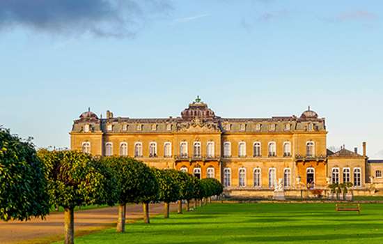 Looking across lawns to the large French-looking country house (Wrest Park) which looks amber in the evening sun Looking across lawns to the large French-looking country house (Wrest Park) which looks amber in the evening sun