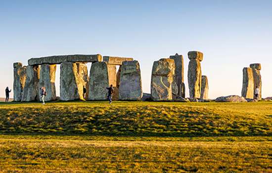 The large stone circle of Stonehenge seen across some grass The large stone circle of Stonehenge seen across some grass