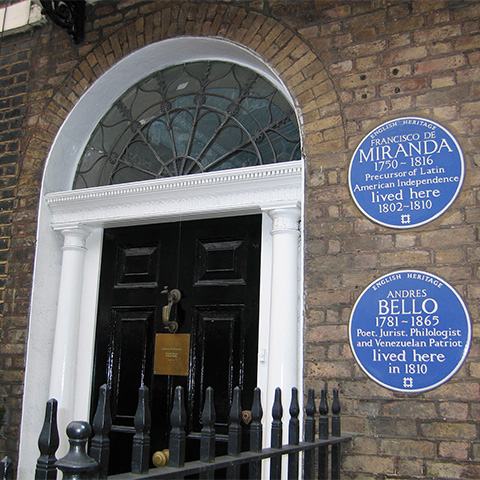 A doorway with two blue plaques dedicated to Francisco de Miranda and Andres Bello on the exterior wall.